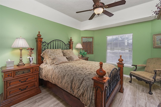 bedroom with ceiling fan, light hardwood / wood-style floors, and a textured ceiling