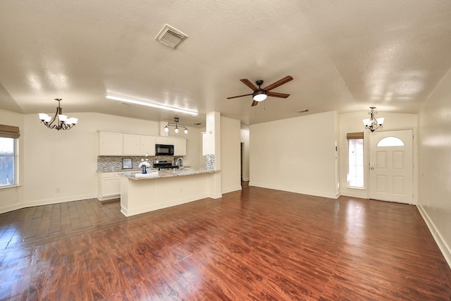 kitchen featuring tasteful backsplash, white cabinets, kitchen peninsula, and lofted ceiling