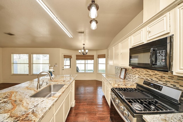 kitchen featuring tasteful backsplash, gas range, light stone countertops, pendant lighting, and sink