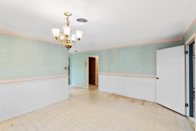 empty room with crown molding and a chandelier