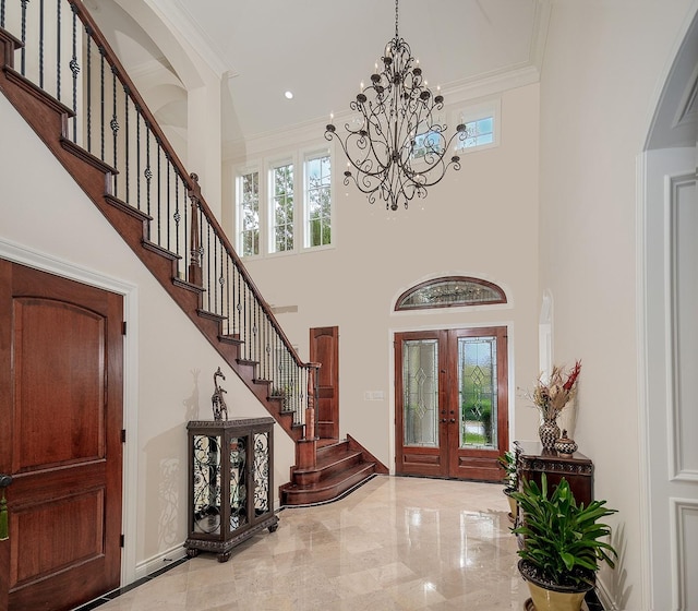 entrance foyer with crown molding, a towering ceiling, and french doors