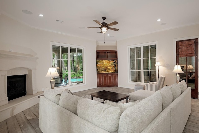 living room featuring ceiling fan, ornamental molding, and wood-type flooring