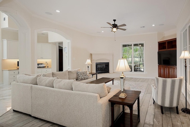 living room with light wood-type flooring, ceiling fan, and crown molding