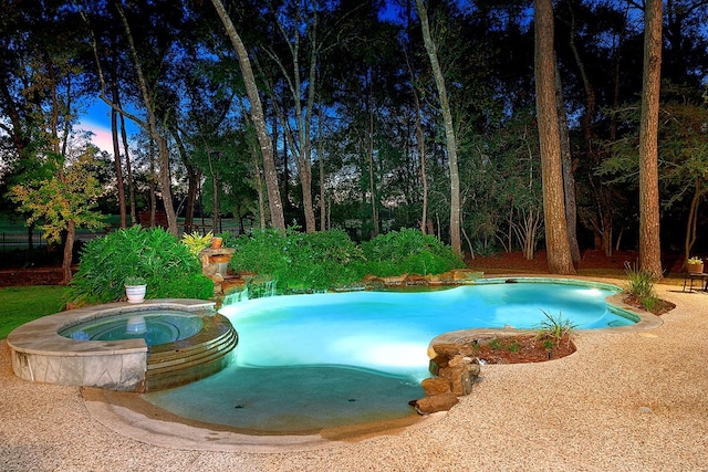 pool at dusk with an in ground hot tub