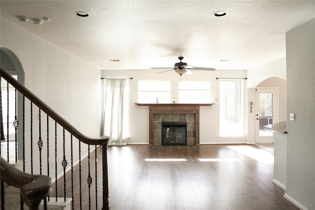 unfurnished living room featuring a fireplace, wood-type flooring, a textured ceiling, and ceiling fan