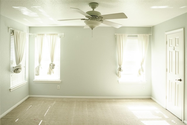 spare room with ceiling fan and light carpet