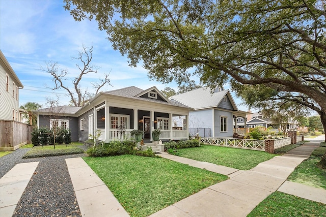 bungalow featuring covered porch and a front yard