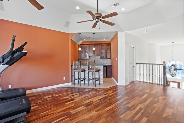 interior space featuring vaulted ceiling, dark wood-type flooring, and ceiling fan with notable chandelier