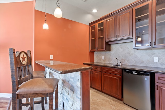 kitchen with tasteful backsplash, sink, hanging light fixtures, a kitchen breakfast bar, and fridge