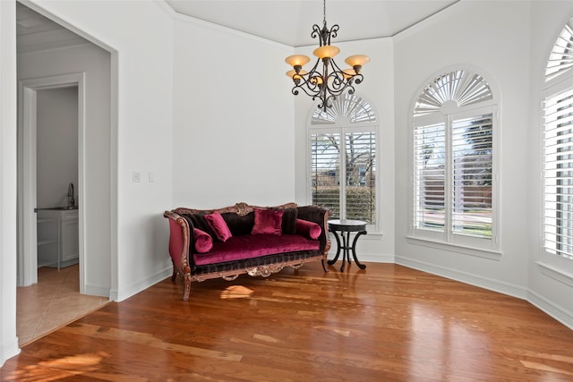 sitting room with wood-type flooring, ornamental molding, and a notable chandelier