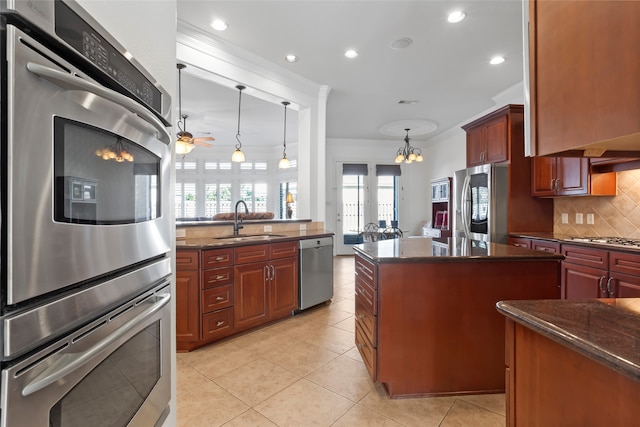 kitchen with ceiling fan with notable chandelier, pendant lighting, stainless steel appliances, decorative backsplash, and sink