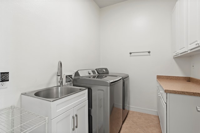 laundry area featuring cabinets, separate washer and dryer, light tile patterned flooring, and sink