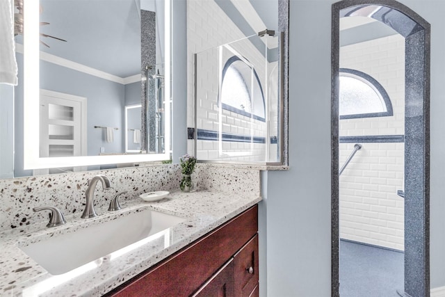 bathroom with crown molding, tiled shower, and vanity