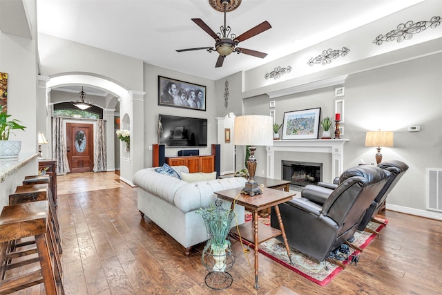 living room featuring ceiling fan, dark hardwood / wood-style floors, and decorative columns