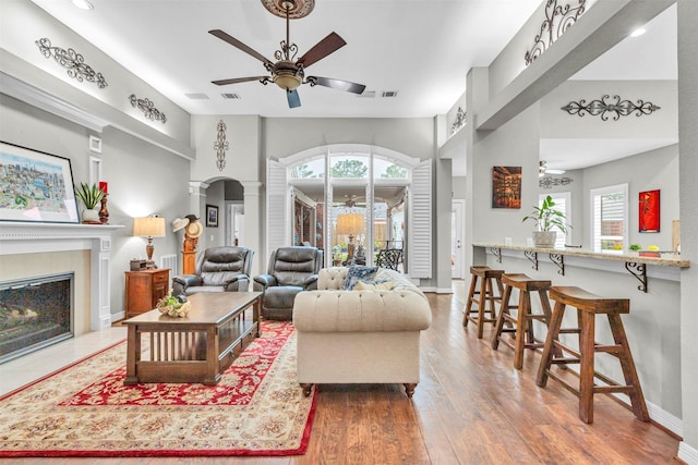 living room featuring hardwood / wood-style flooring, ceiling fan, and ornate columns