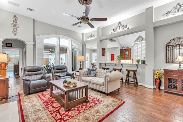 living room featuring decorative columns, hardwood / wood-style floors, and ceiling fan