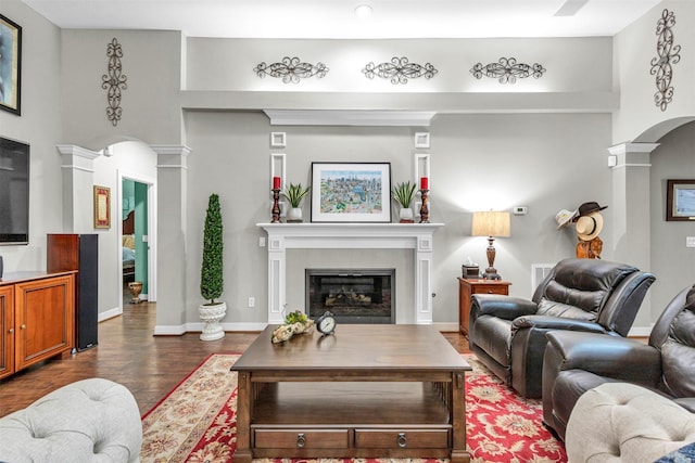 living room with dark hardwood / wood-style flooring, a tiled fireplace, and decorative columns