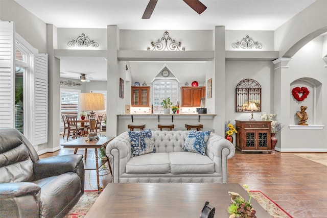 living room with hardwood / wood-style flooring, ceiling fan, and a towering ceiling