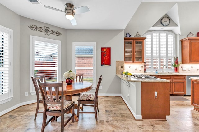 kitchen with appliances with stainless steel finishes, a healthy amount of sunlight, light stone counters, and decorative backsplash