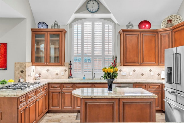 kitchen with light stone countertops, appliances with stainless steel finishes, sink, and lofted ceiling