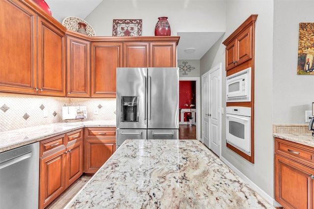 kitchen with tasteful backsplash, light stone countertops, stainless steel appliances, and lofted ceiling