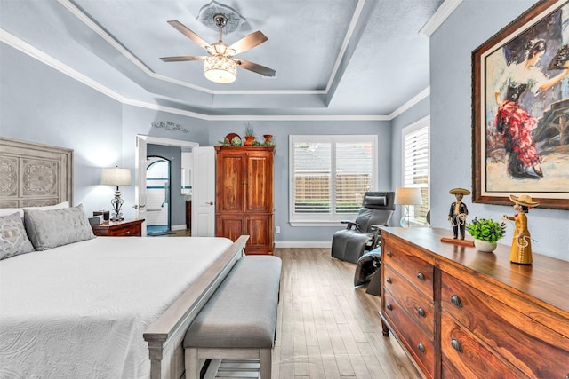 bedroom with a tray ceiling, ornamental molding, ceiling fan, and light wood-type flooring