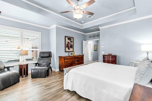 bedroom with ornamental molding, light hardwood / wood-style floors, a raised ceiling, and ceiling fan