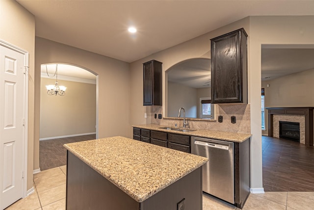 kitchen featuring a center island, stainless steel dishwasher, sink, dark brown cabinetry, and light tile patterned floors