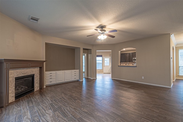 unfurnished living room featuring ceiling fan, dark hardwood / wood-style flooring, and a textured ceiling