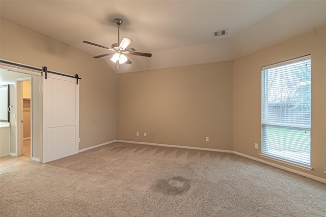 carpeted empty room with ceiling fan, a barn door, and vaulted ceiling