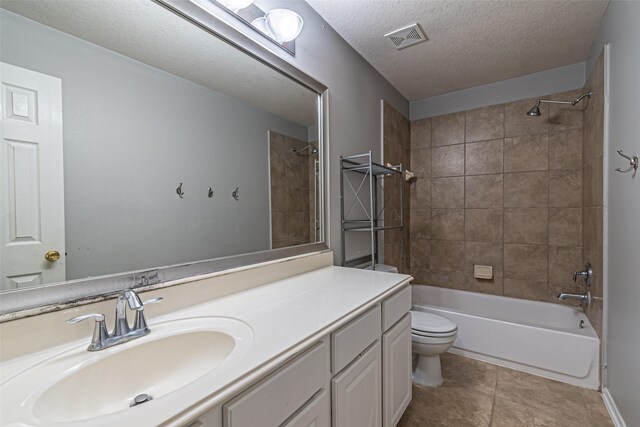 full bathroom with toilet, vanity, tile patterned flooring, tiled shower / bath combo, and a textured ceiling