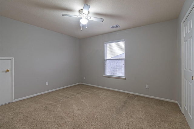 carpeted spare room featuring ceiling fan and a textured ceiling