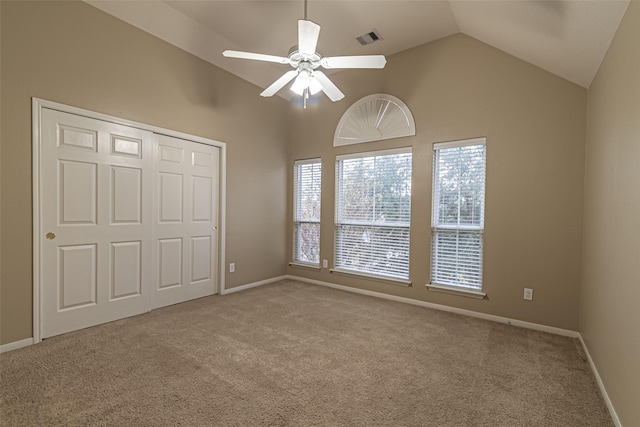 unfurnished bedroom with light carpet, ceiling fan, a closet, and high vaulted ceiling