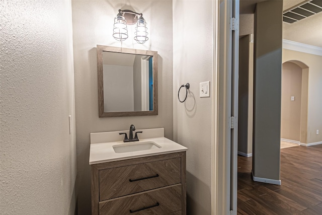 bathroom with vanity, ornamental molding, and hardwood / wood-style flooring