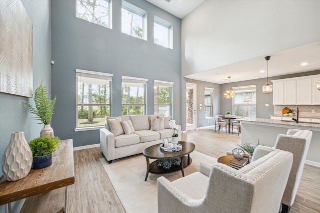 living room featuring light hardwood / wood-style floors, sink, and a high ceiling