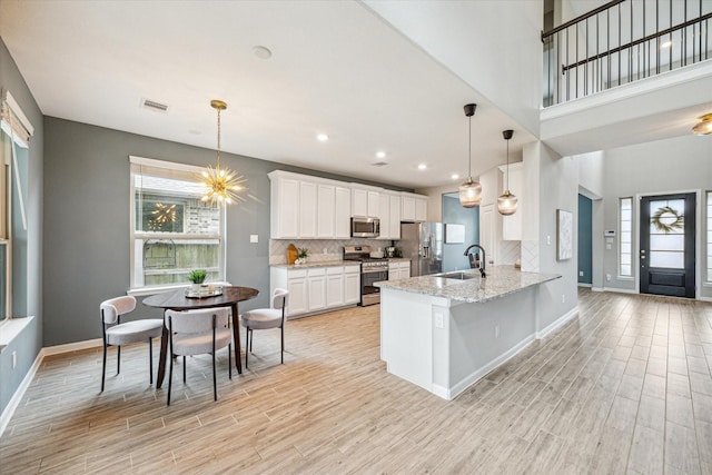 kitchen featuring light stone countertops, white cabinets, appliances with stainless steel finishes, tasteful backsplash, and kitchen peninsula