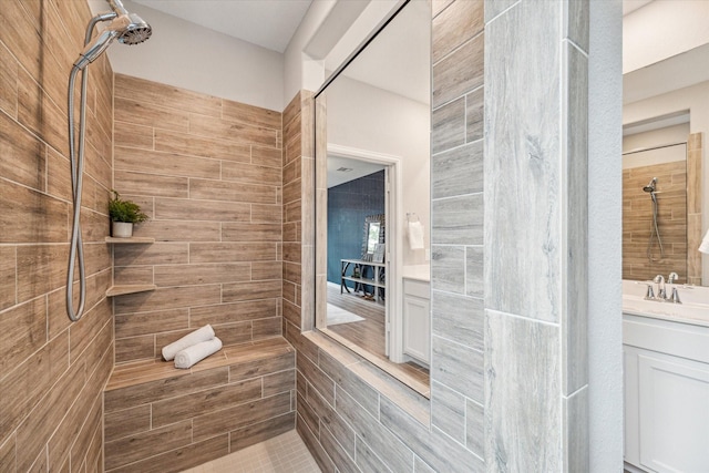 bathroom with tiled shower and vanity