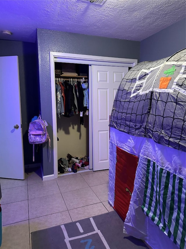 bedroom featuring a closet, tile patterned floors, and a textured ceiling