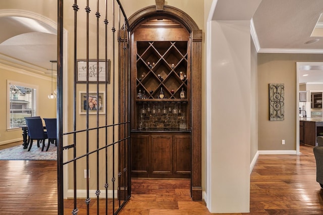 wine area with crown molding and dark hardwood / wood-style flooring