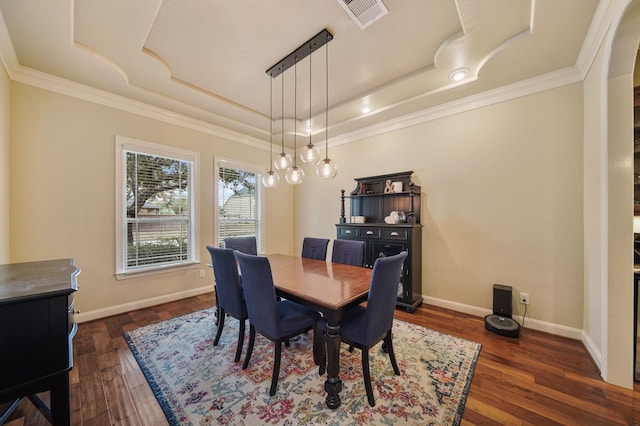 dining space featuring dark wood-type flooring, crown molding, and a raised ceiling