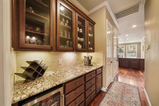 bar featuring crown molding, wine cooler, dark wood-type flooring, tasteful backsplash, and light stone countertops