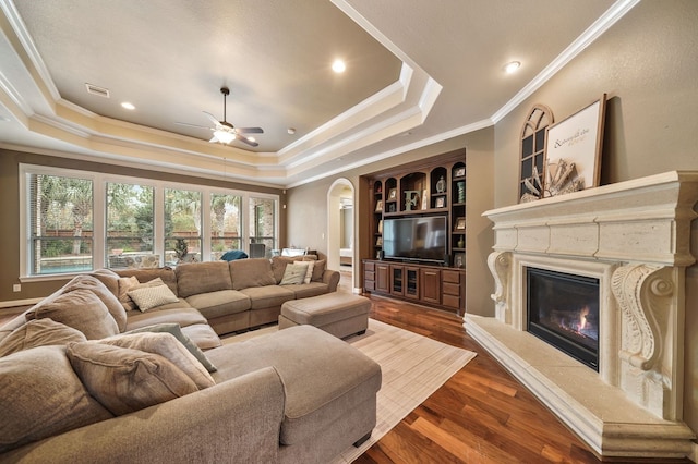 living room with hardwood / wood-style flooring, ornamental molding, a raised ceiling, and ceiling fan