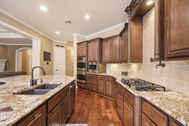 kitchen with sink, ornamental molding, dark wood-type flooring, stainless steel appliances, and light stone counters