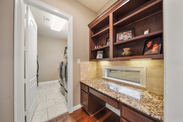 kitchen featuring light stone countertops, hardwood / wood-style floors, built in desk, decorative backsplash, and independent washer and dryer