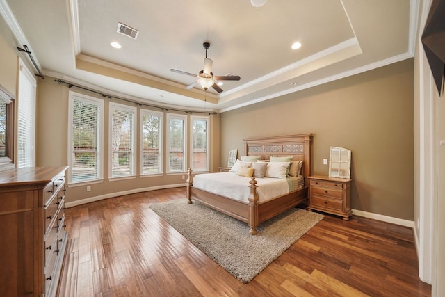 bedroom with ceiling fan, ornamental molding, hardwood / wood-style floors, and a tray ceiling