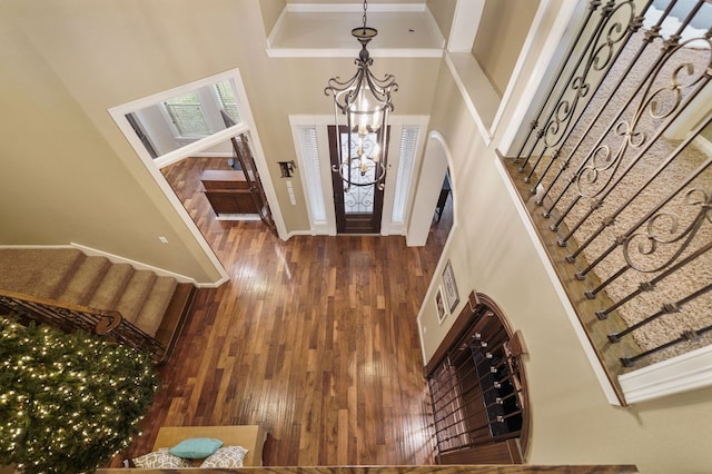 entrance foyer featuring a high ceiling, dark hardwood / wood-style floors, crown molding, and an inviting chandelier