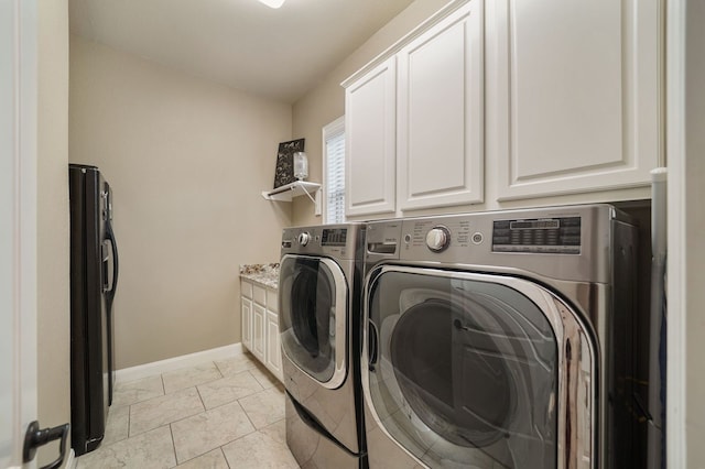 laundry room with light tile patterned floors, cabinets, and washer and clothes dryer