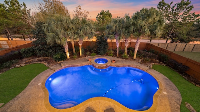 pool at dusk featuring an in ground hot tub and a yard