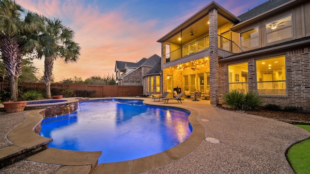 pool at dusk featuring an in ground hot tub, a patio, ceiling fan, and pool water feature