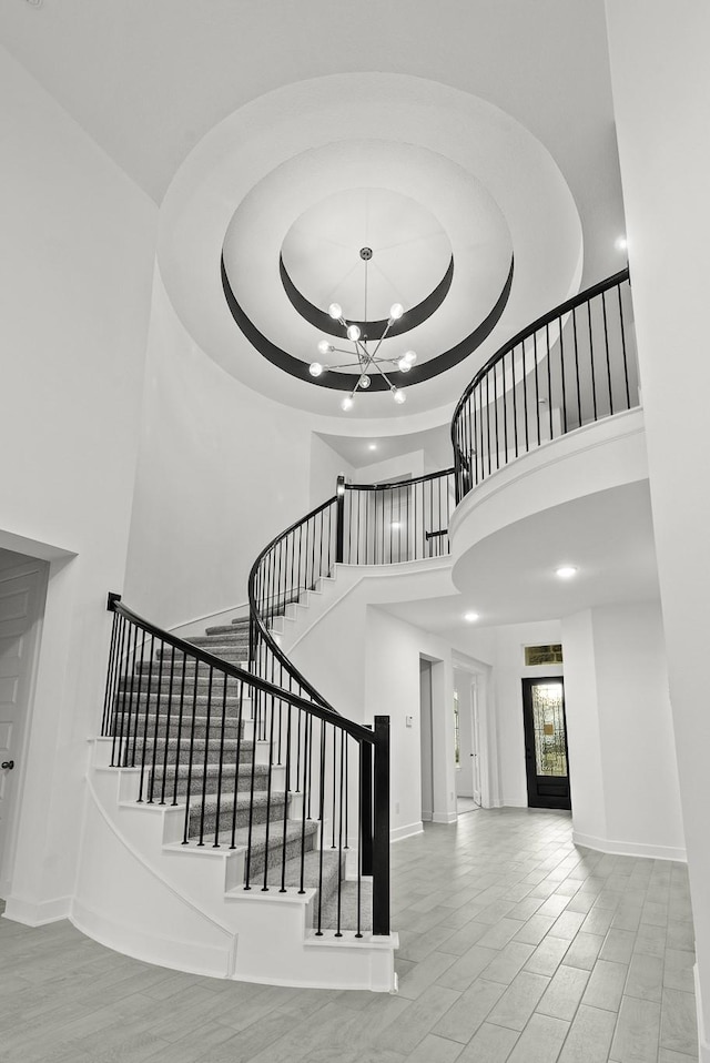 stairway featuring a towering ceiling and an inviting chandelier